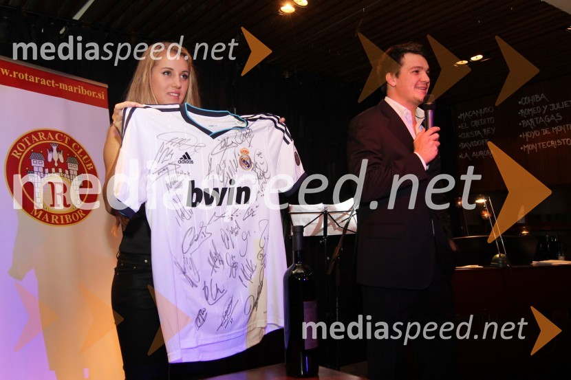 	Tajda Lah, hostesa, uradni dres nogometne ekipe FC Real Madrid z podpisi igralcev ter Mitja Šeško član Rotaract Cluba MariborTradicionalna dobrodelna večerja in licitacija Rotaract Cluba Maribor